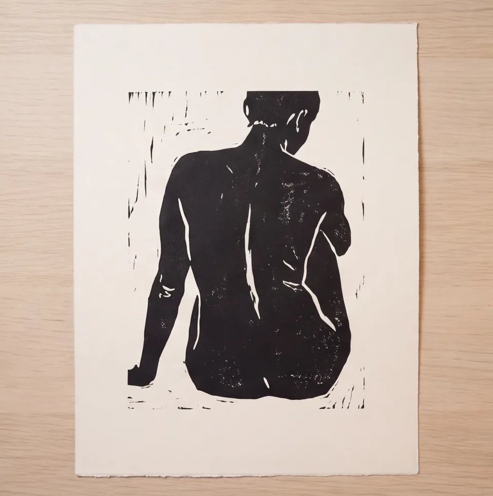 A linocut print of a seated figure